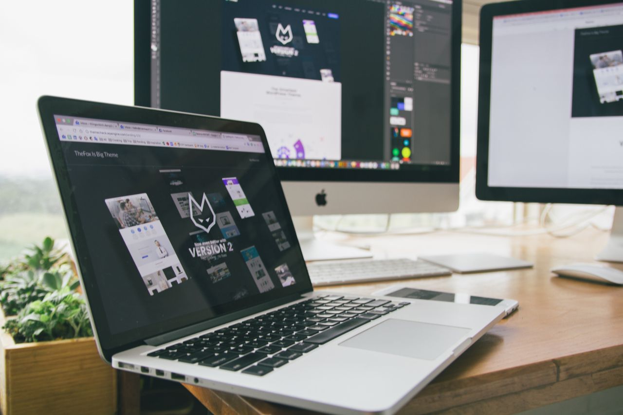who-we-are A stylish workspace featuring a laptop and monitors displaying design software.
